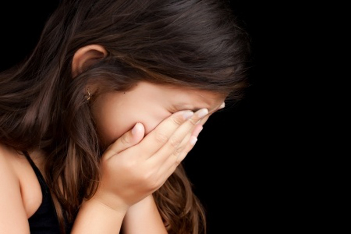 girl crying with her hands on her face