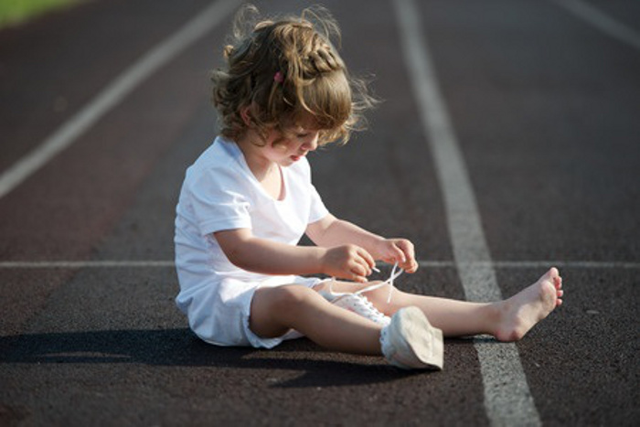 girl learning to tie shoelaces.