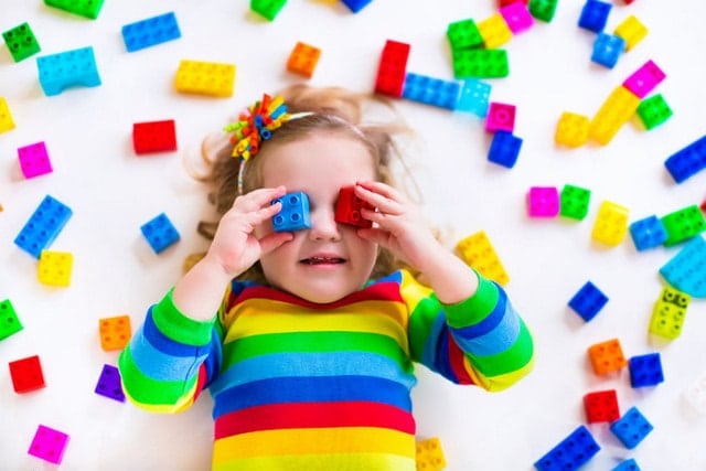 little girl playing with construction toy blocks